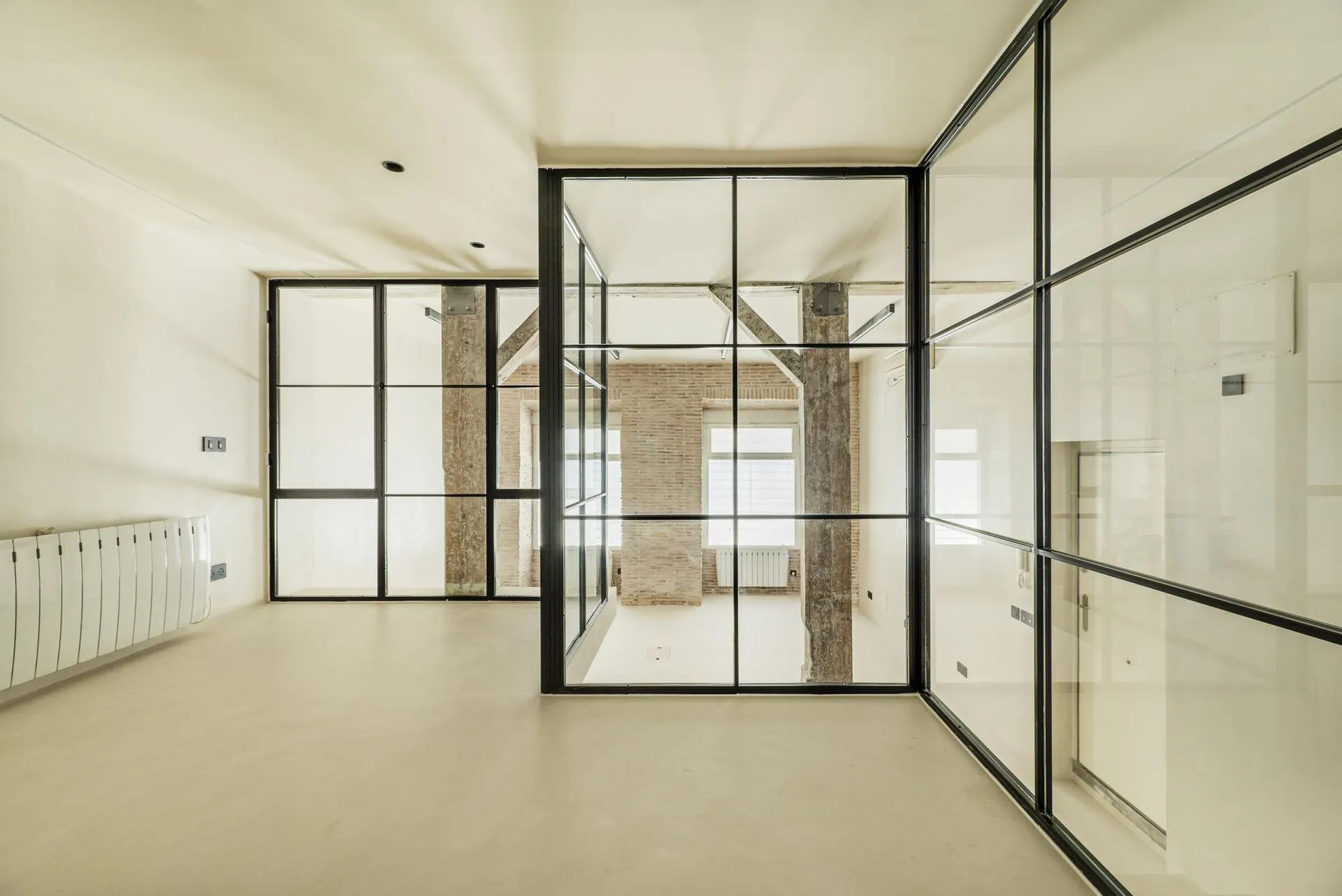 Black-framed interior glass partitions dividing an open, sunlit room.